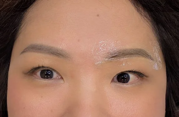Mid-procedure, soothing balm still on one brow