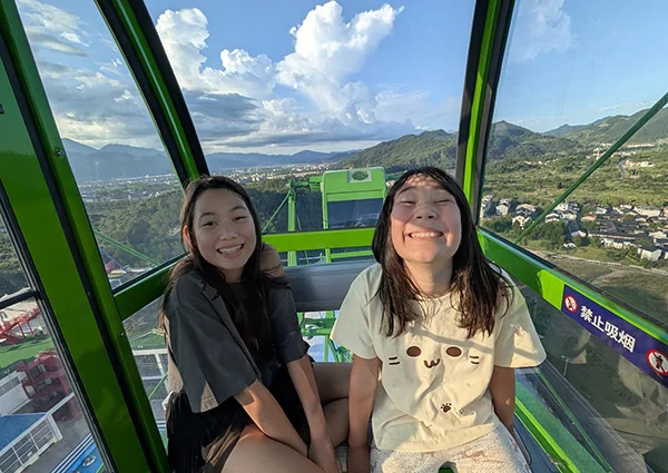 The two girls grinning inside a Ferris wheel cabin