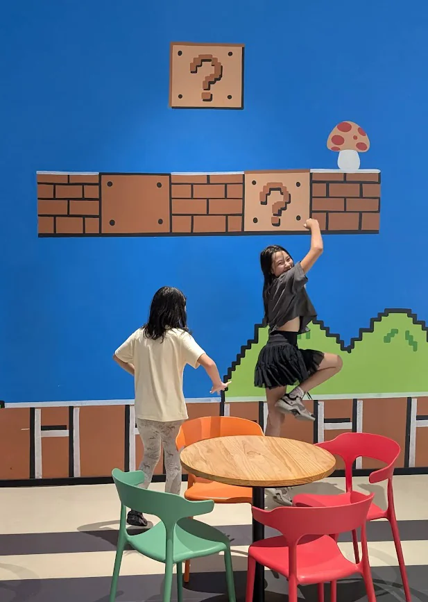 The girls posing in front of a Super Mario themed wall