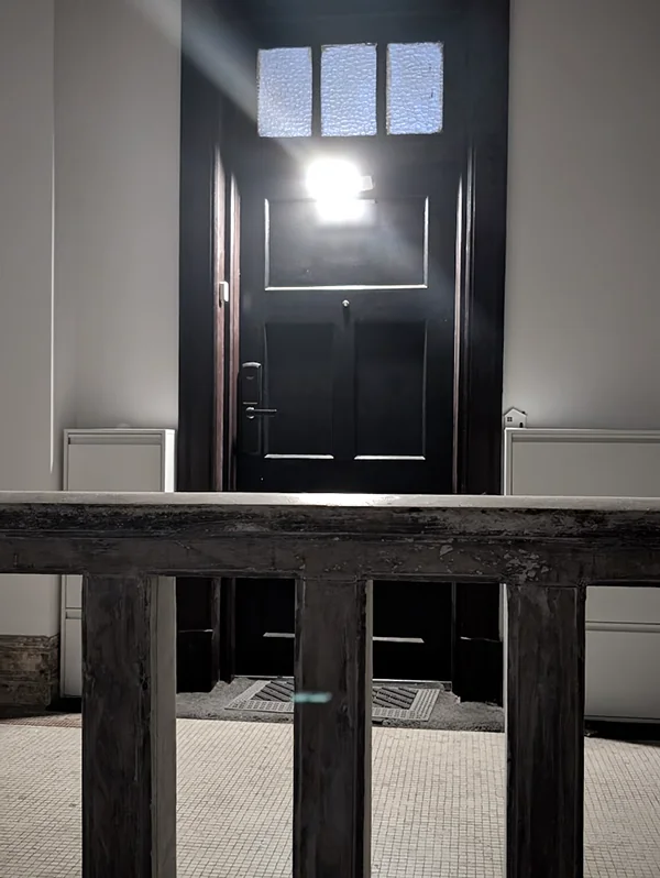 The dark old apartment door at the top of the stairs