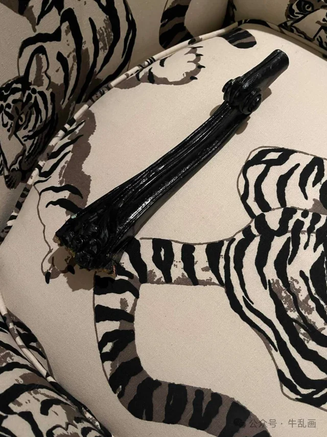 The broken black chair leg lying on the tiger-print chaise