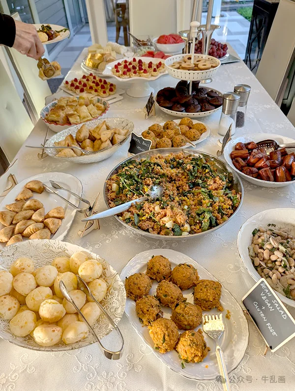 A potluck table loaded with Mediterranean dishes, pastries and salads