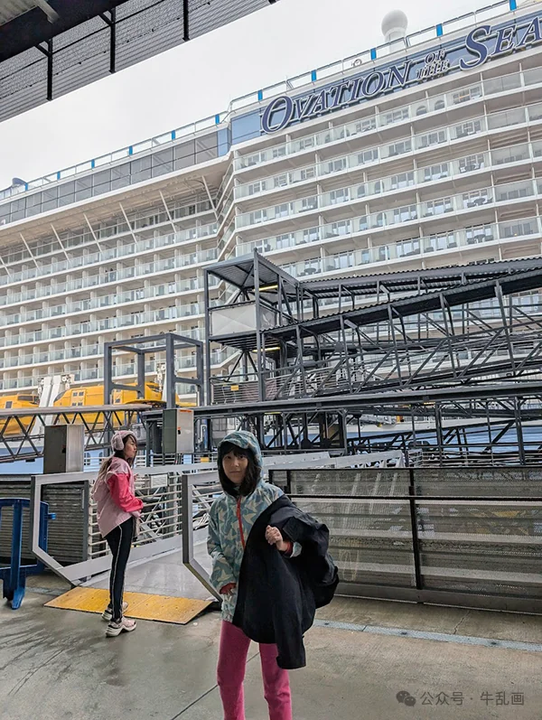 The girls in rain jackets in front of the enormous Ovation of the Seas at the pier