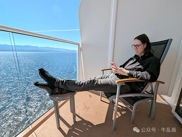 Niu-ba lounging on the balcony with his feet up on a stool, ocean behind