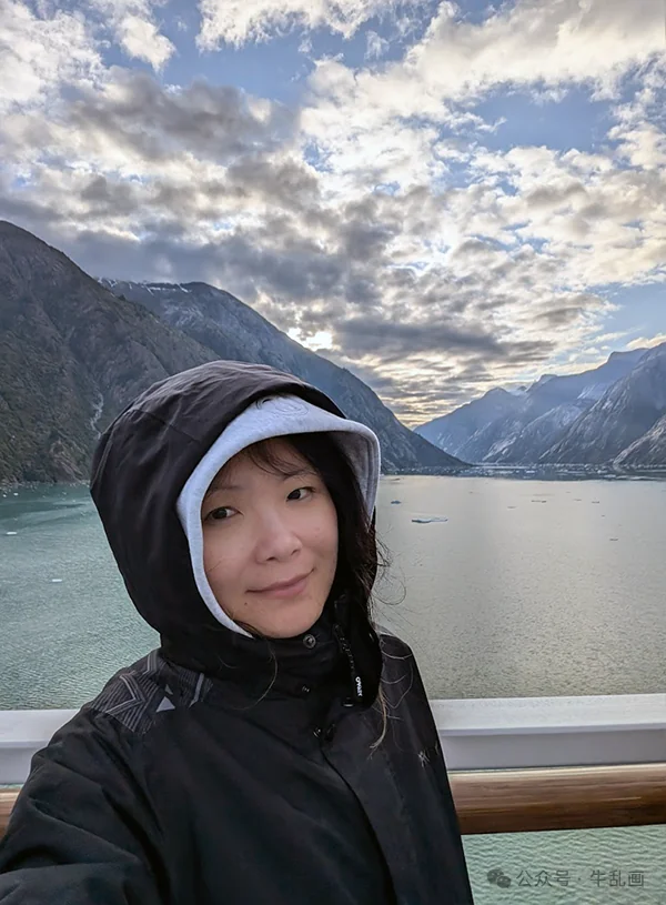 Niu-ma in a hooded jacket on deck at dawn, mountains and clouds behind