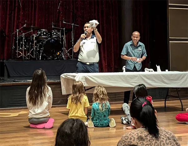A crew member teaching a towel-animal folding class on stage